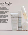 Barrier boosting microbiome care display with four skincare products arranged left to right a cleanser tube a serum bottle a moisturizer bottle and a cream jar on a soft gradient backdrop
