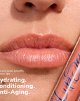 Close up of glossy lips with a LipSense gloss tube beside them showing a peachy shade